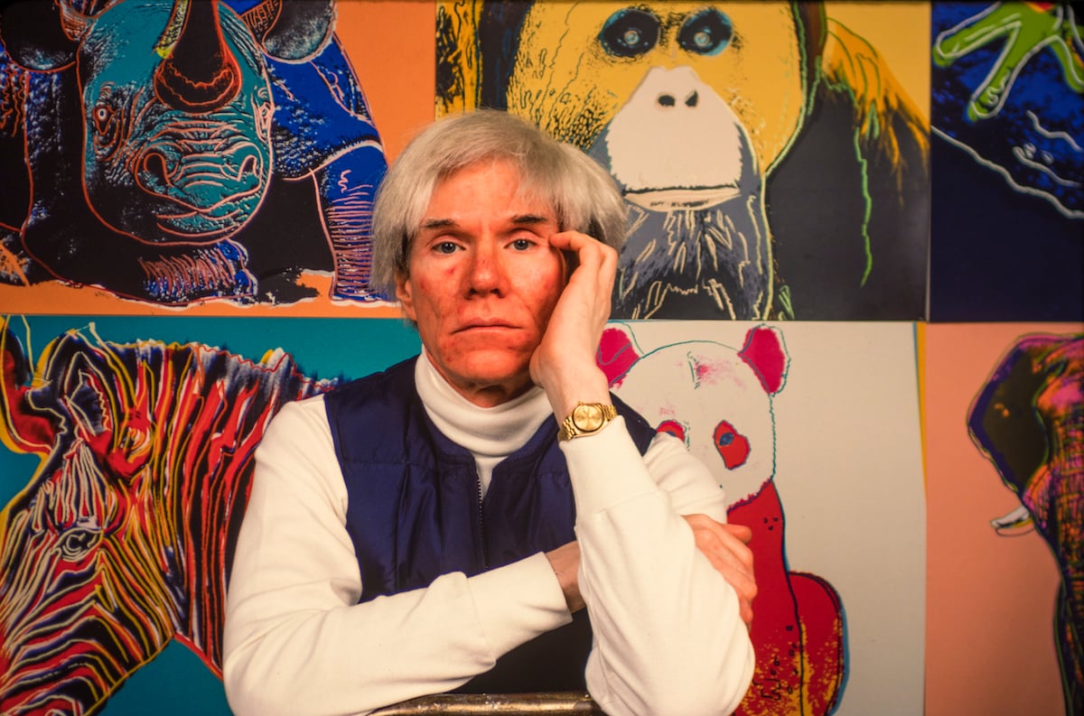 Andy Warhol sits in front of several paintings in his 'Endangered Species' at his studio, the Factory
