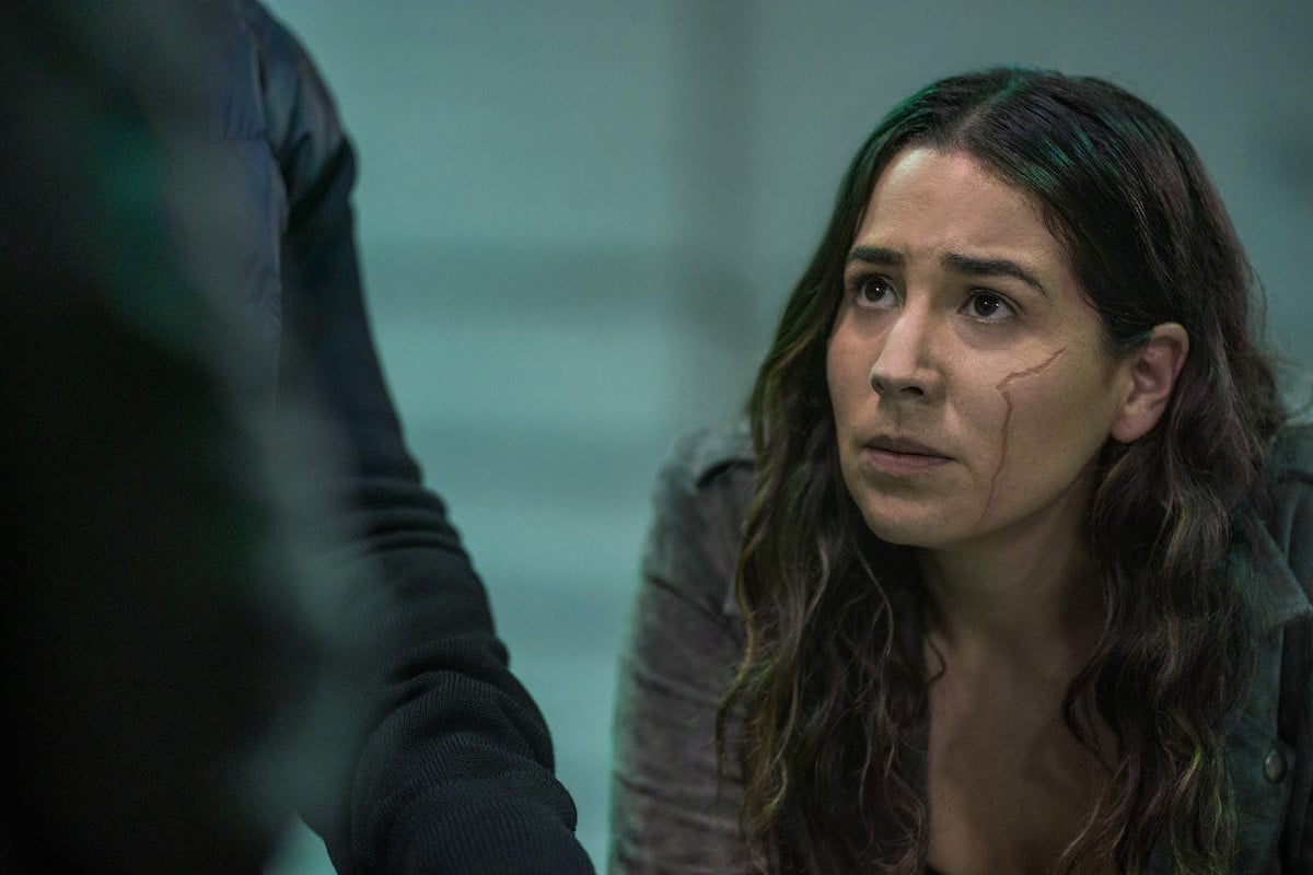 Audrey Esparza dresses as her 'Power Book IV: Force' character Liliana wearing a dark-colored outfit with her hair hanging loosely around her shoulders