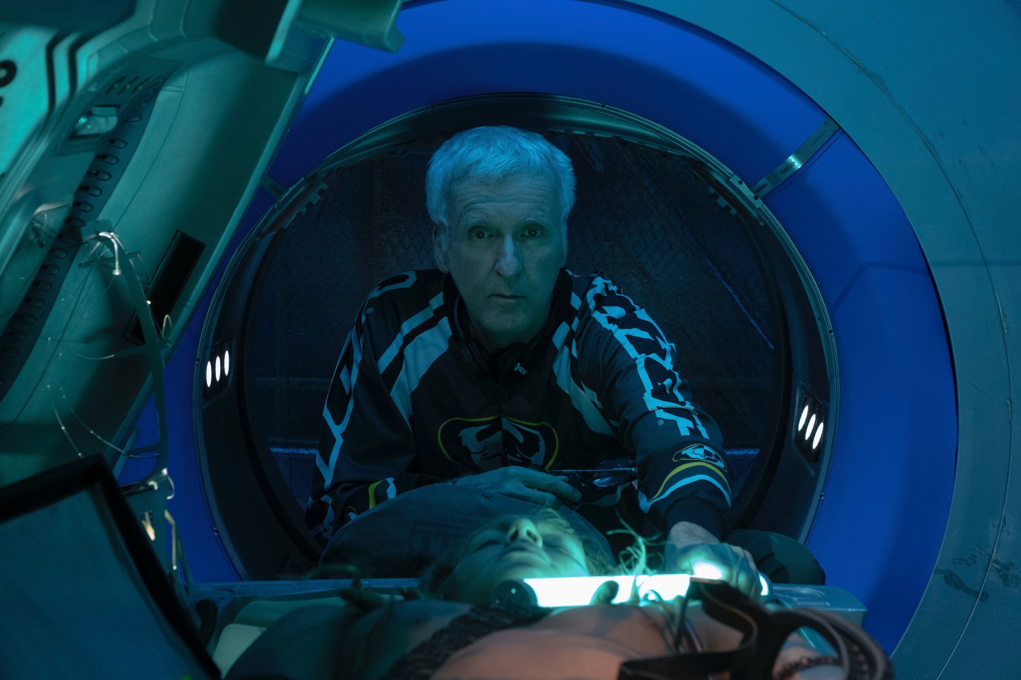 'Avatar 2' James Cameron behind the scenes leaning forward holding a tube light over a body