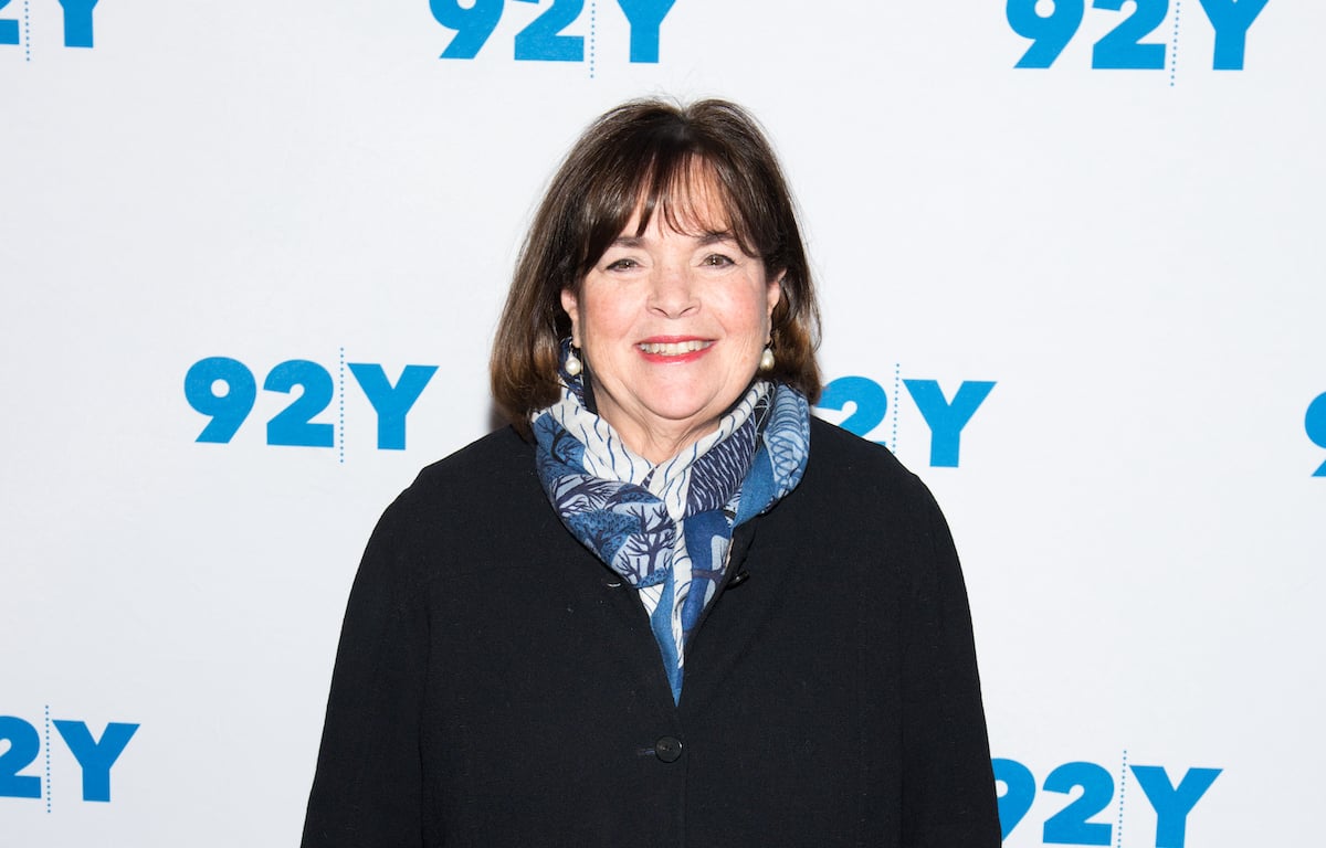 'Be My Guest With Ina Garten' host Ina Garten smiles wearing a black shirt and blue scarf