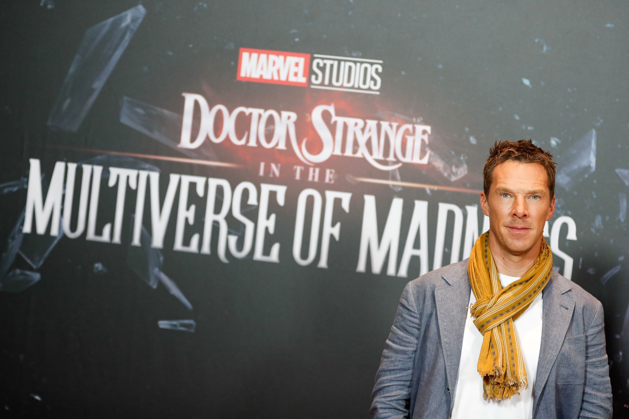 Benedict Cumberbatch, who plays Midnight Sons member Doctor Strange in 'Doctor Strange 2,' wears a gray suit over a white shirt and yellow scarf.