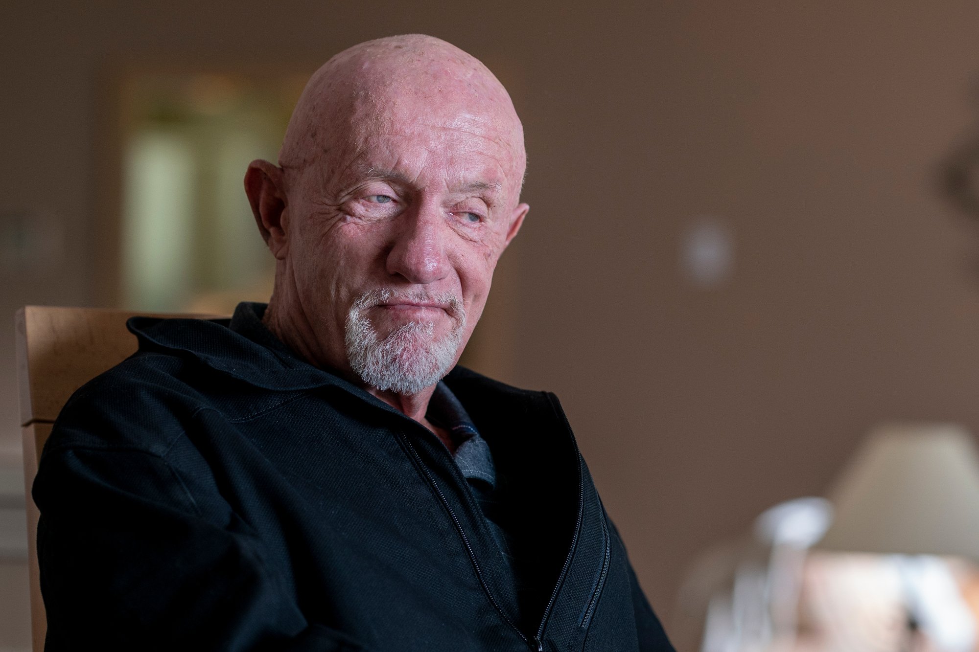 Jonathan Banks as Mike Ehrmantraut in 'Better Call Saul' Season 5. He's wearing a black shirt and smiling.