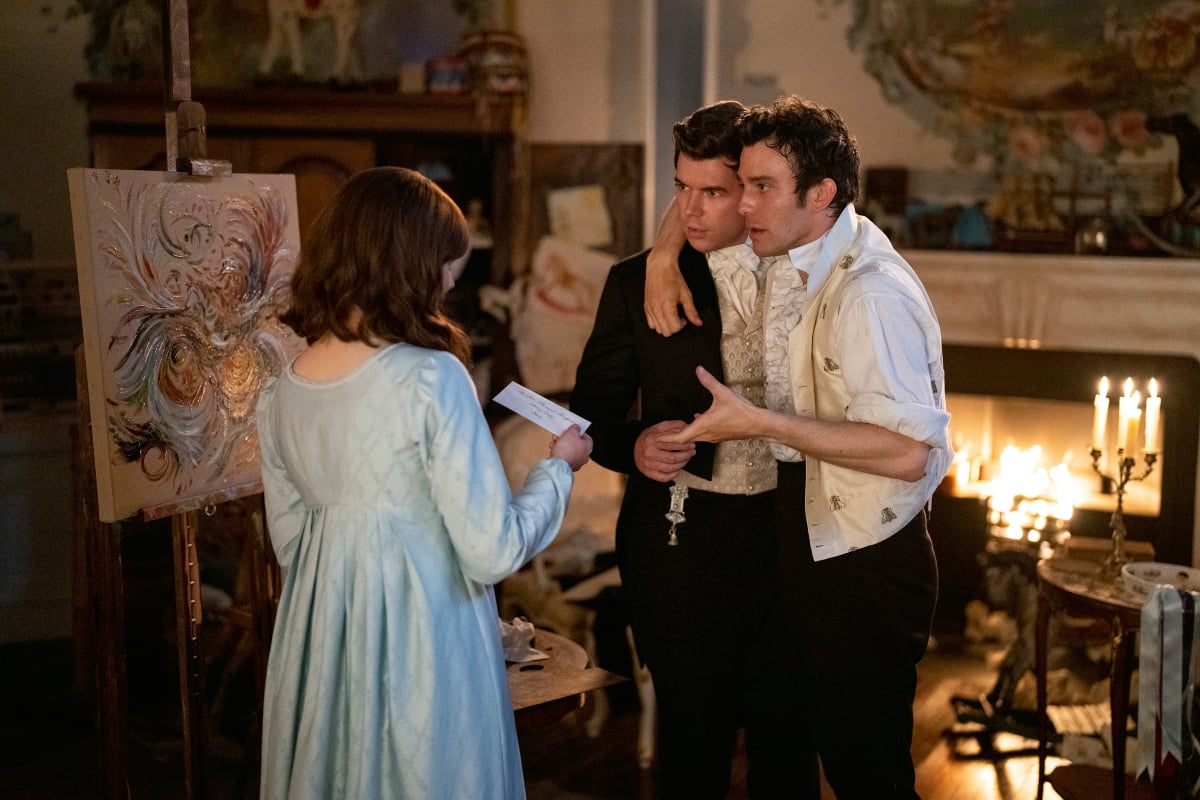 Claudia Jessie as Eloise Bridgerton, Luke Newton as Colin Bridgerton, Luke Thompson as Benedict Bridgerton in Bridgerton Season 2. Eloise holds a letter. Benedict puts his arm around Colin.