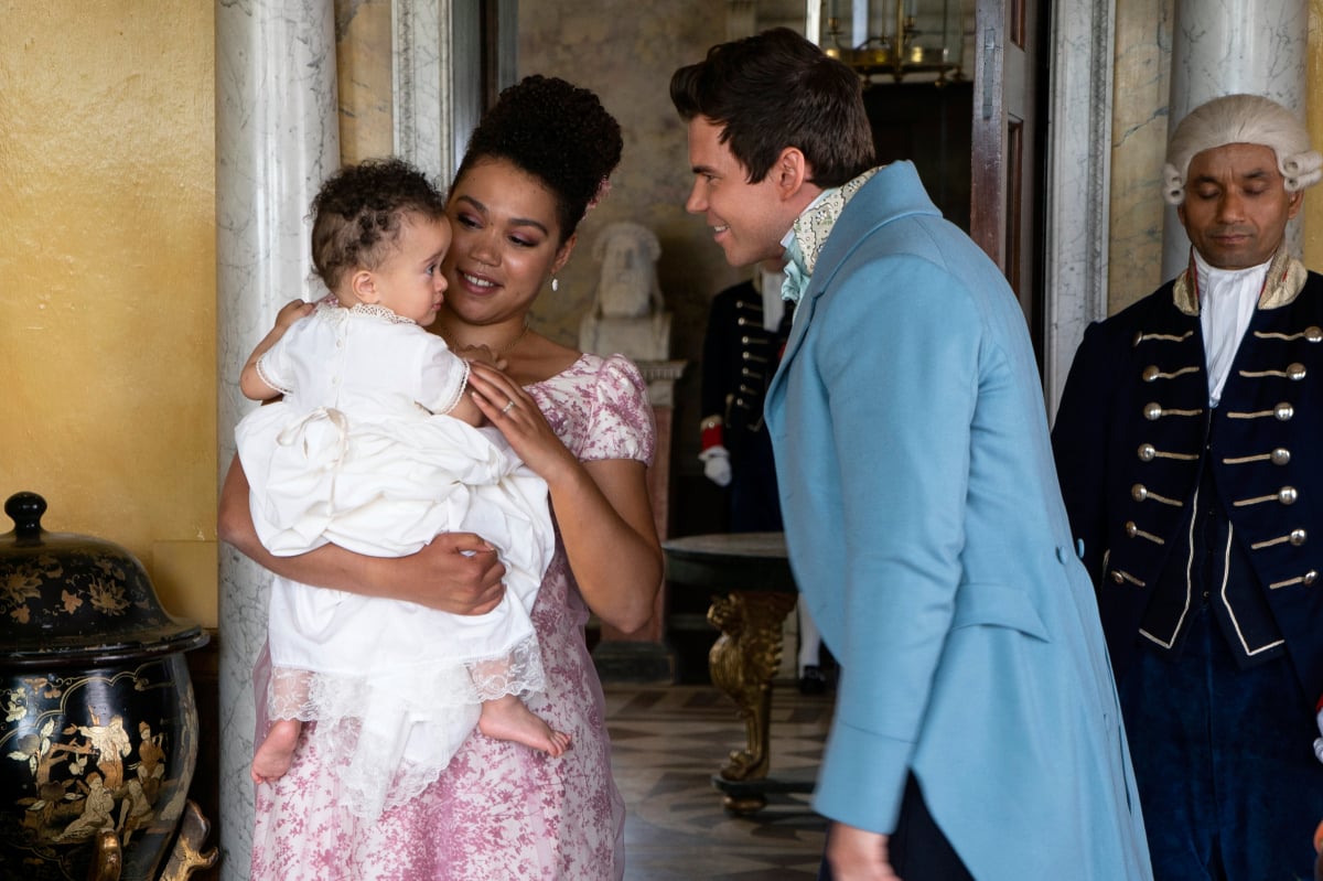 Marina holds her baby and Colin smiles at him in Bridgerton Season 2. 