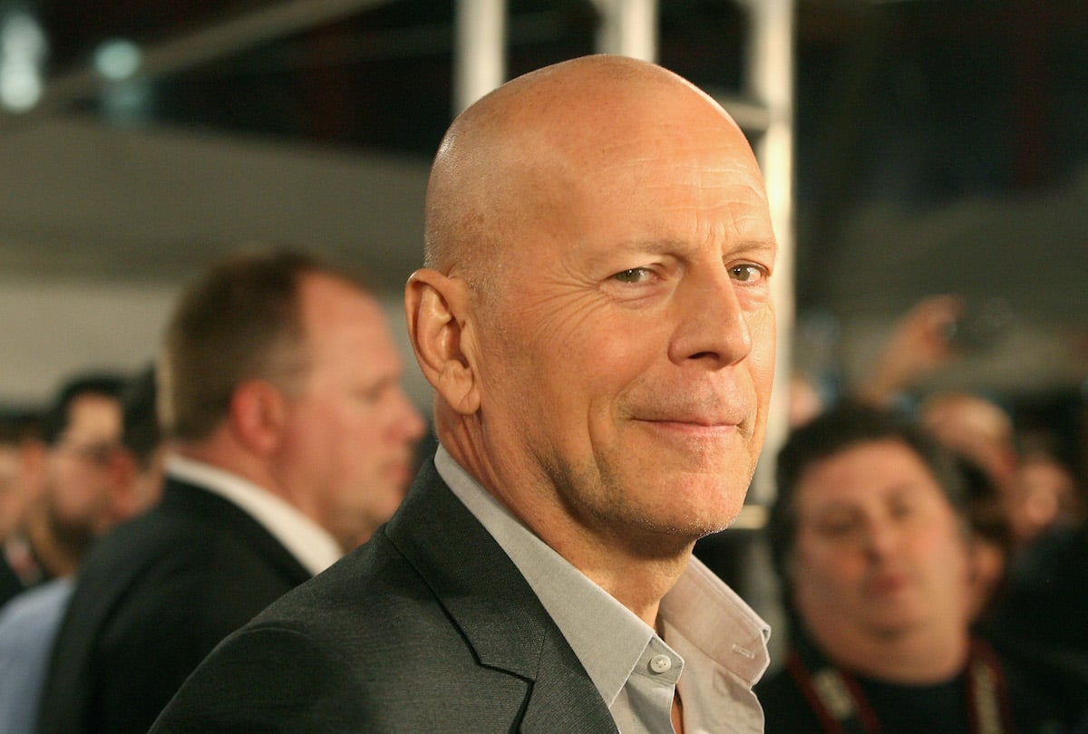 Bruce Willis wears a suit and poses