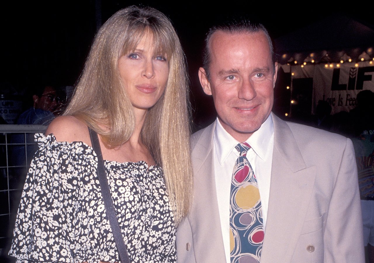 Brynn Hartman in a black and white top, posing with Phil Hartman in a tan suit and patterned tie.