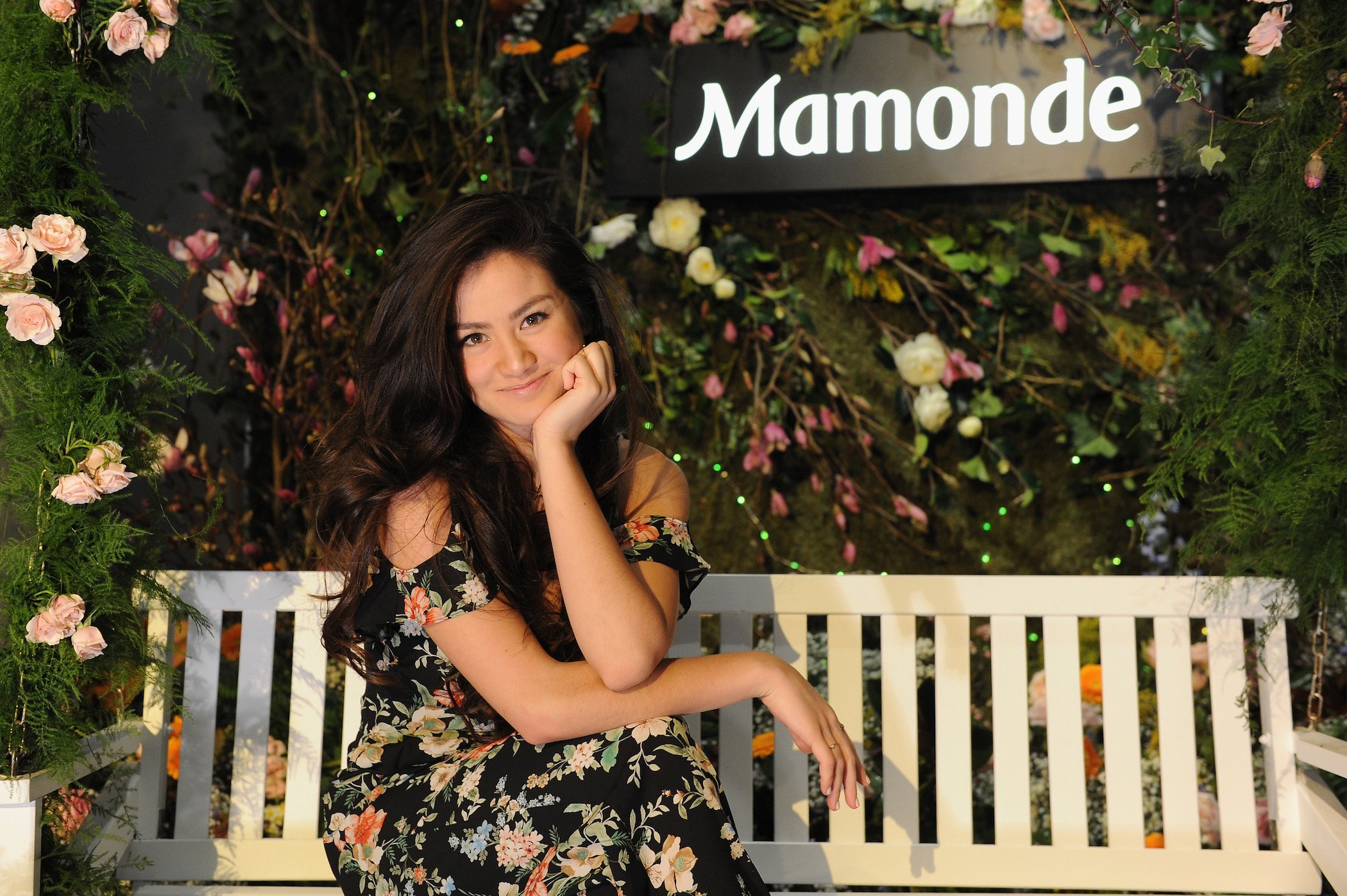 'The Bachelor' star Caila Quinn sitting and smiling against a floral background