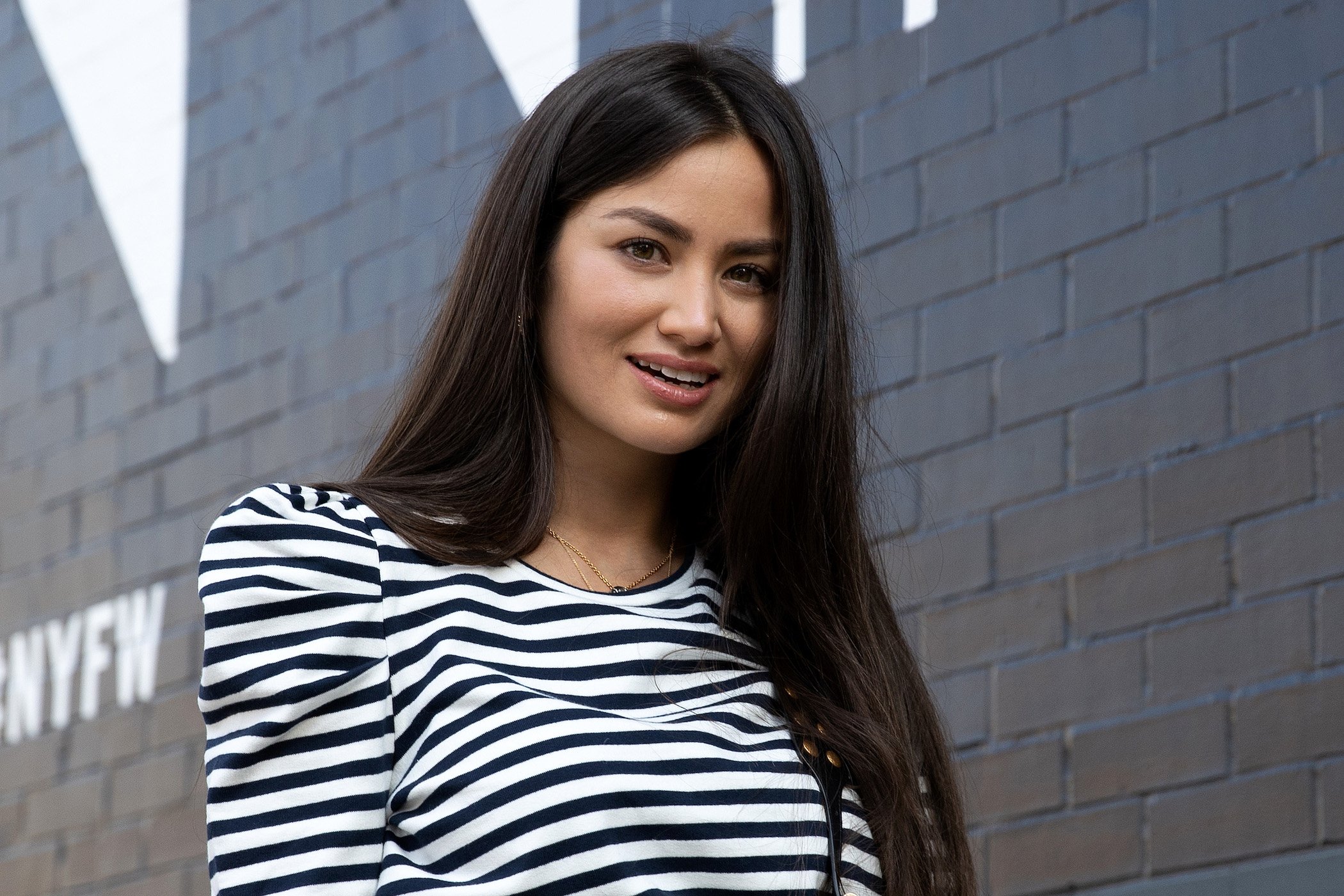 Caila Quinn from 'The Bachelor' smiling while looking at the camera. She's in a striped long-sleeve shirt.