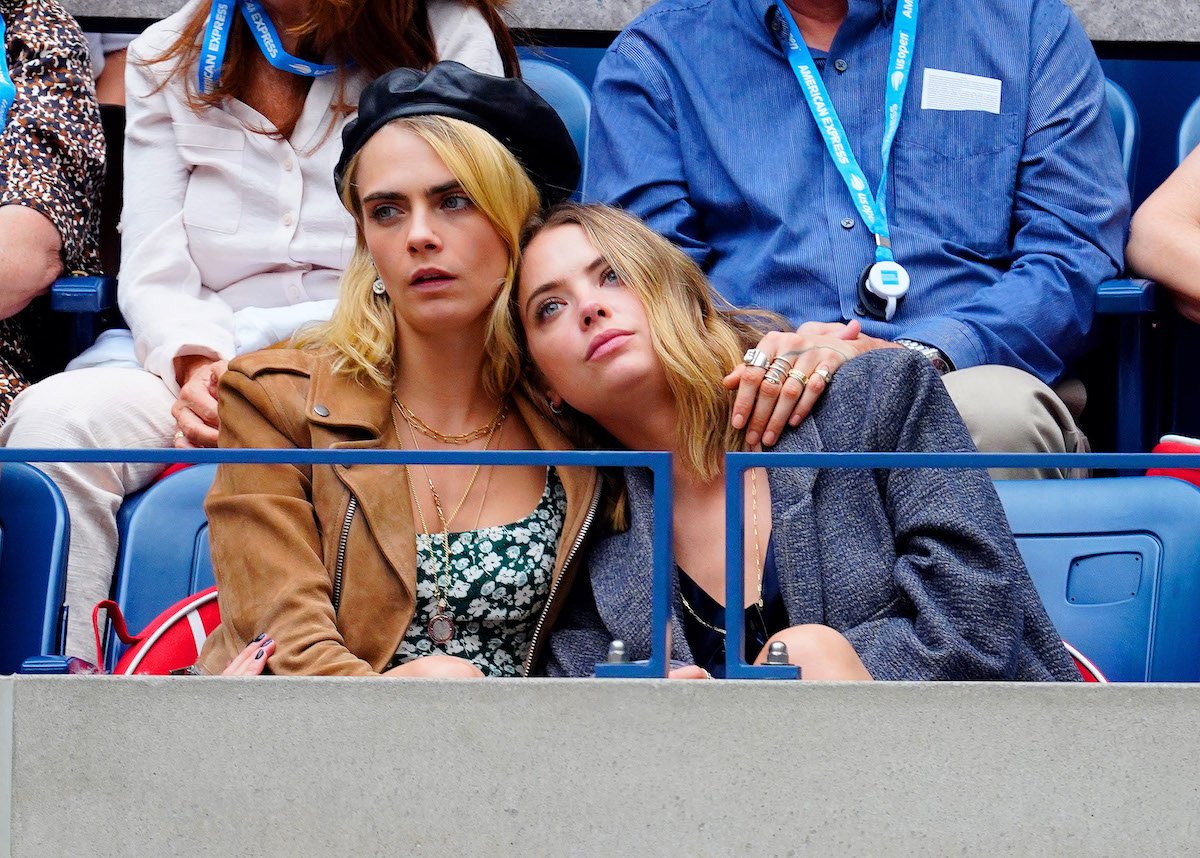 Cara Delevingne puts her arm around Ashley Benson at an event.
