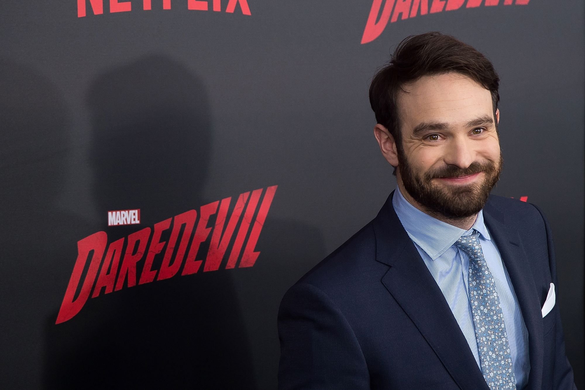 MCU's 'Daredevil' star Charlie Cox wears a dark blue suit over a light blue button-up shirt and blue tie.