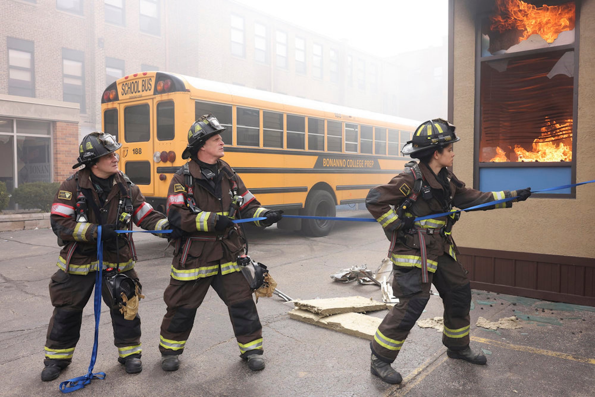 Tony, Harold, and Stella Kidd in firefighting gear outside of a burning school in 'Chicago Fire' Season 10 Episode 19