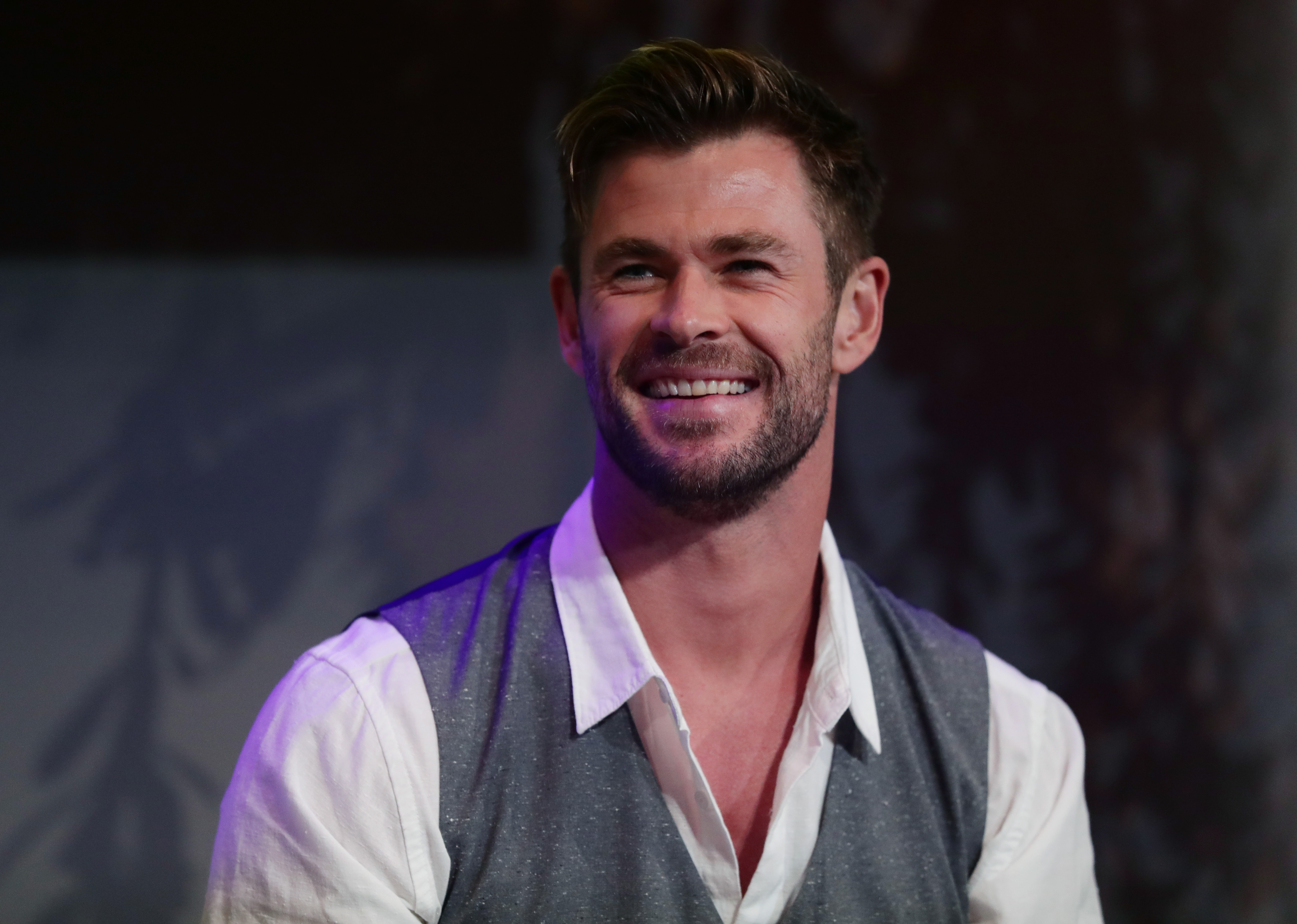 Chris Hemsworth, star of 'Thor: Love and Thunder,' wears a gray vest over a long-sleeved white button-up shirt.