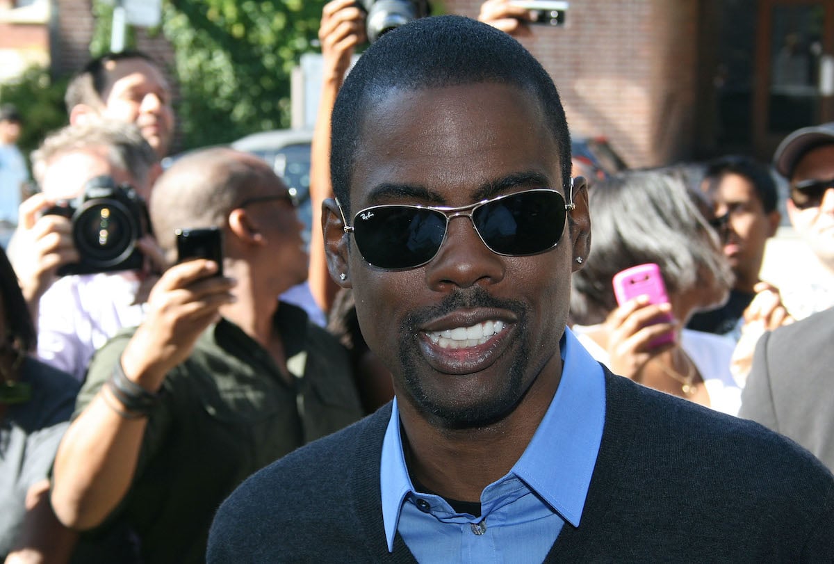 Chris Rock wears sunglasses on the red carpet as fans look on