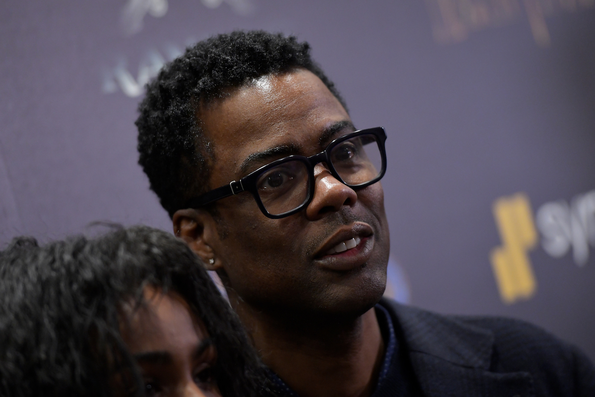 Chris Rock wears glasses and poses on the red carpet