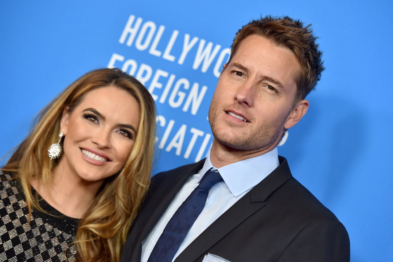 Chrishell Stause and Justin Hartley pose on a red carpet.