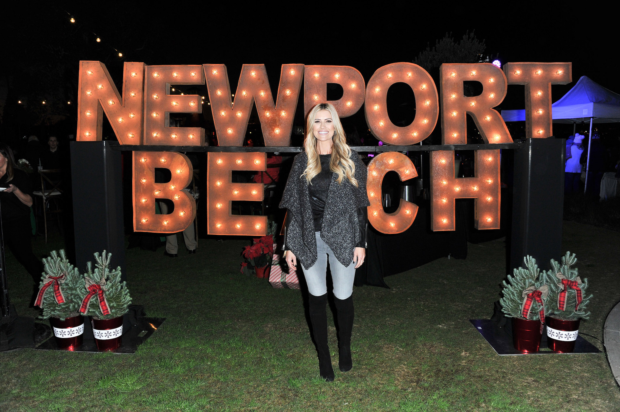 Christina Haack smiling in front of a Newport Beach sign at night