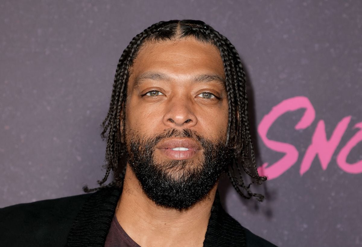 DeRay Davis, who appears on 'Snowfall' as Peaches, poses for a photo in a black suit on the red carpet at an event for the show