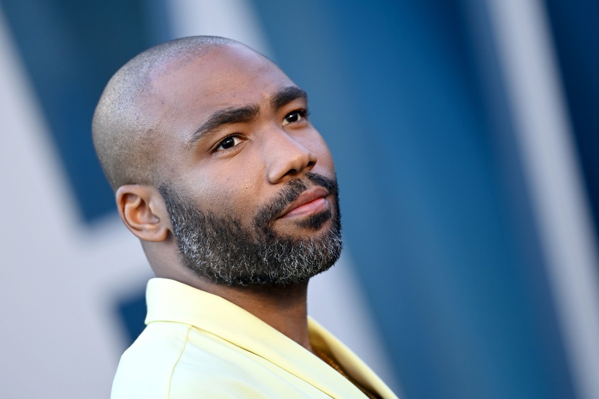 Donald Glover posing while wearing a yellow suit.