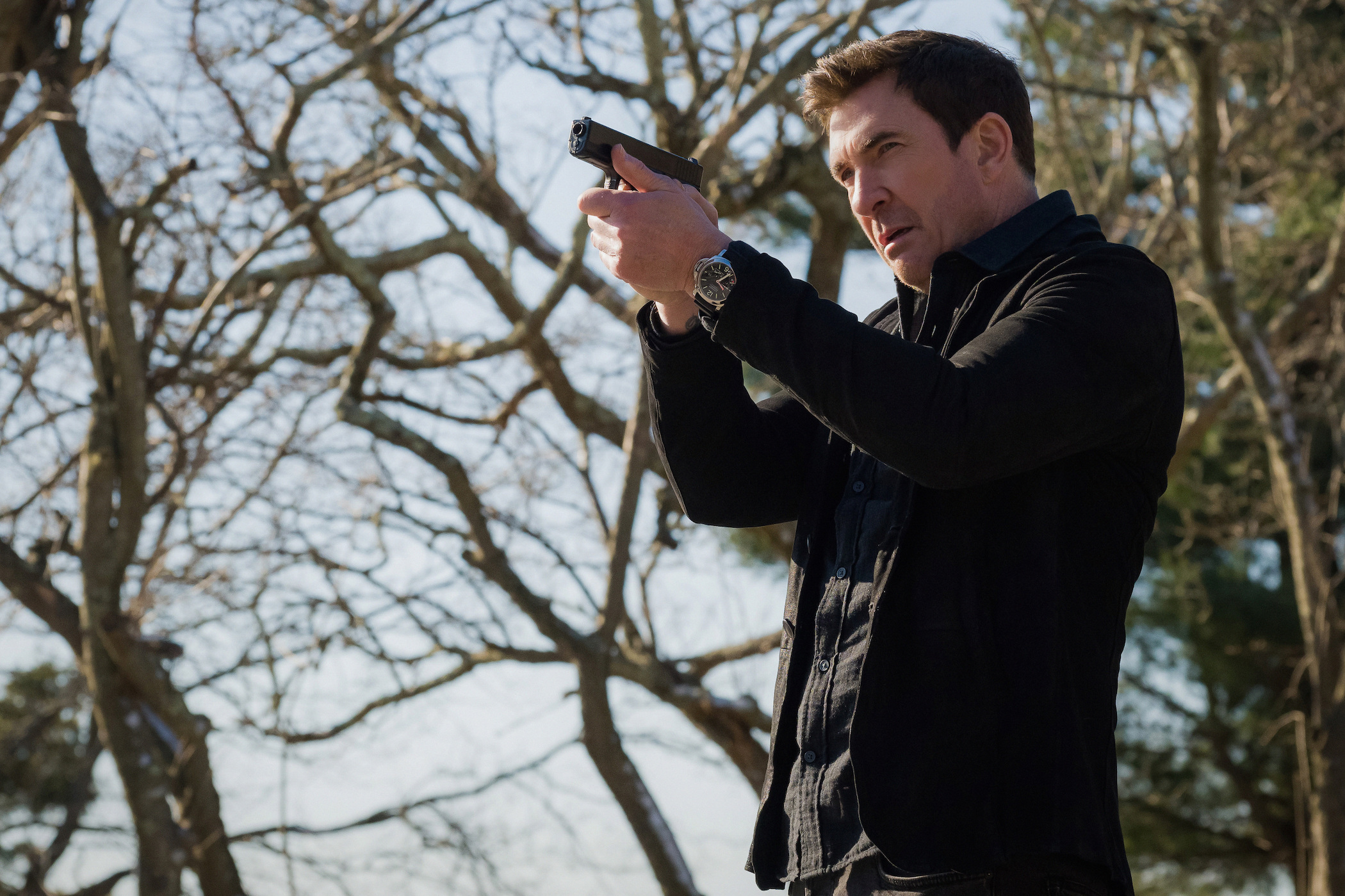 'FBI: Most Wanted' cast member Dylan McDermott as Remy Scott holding a gun ready to shoot outside