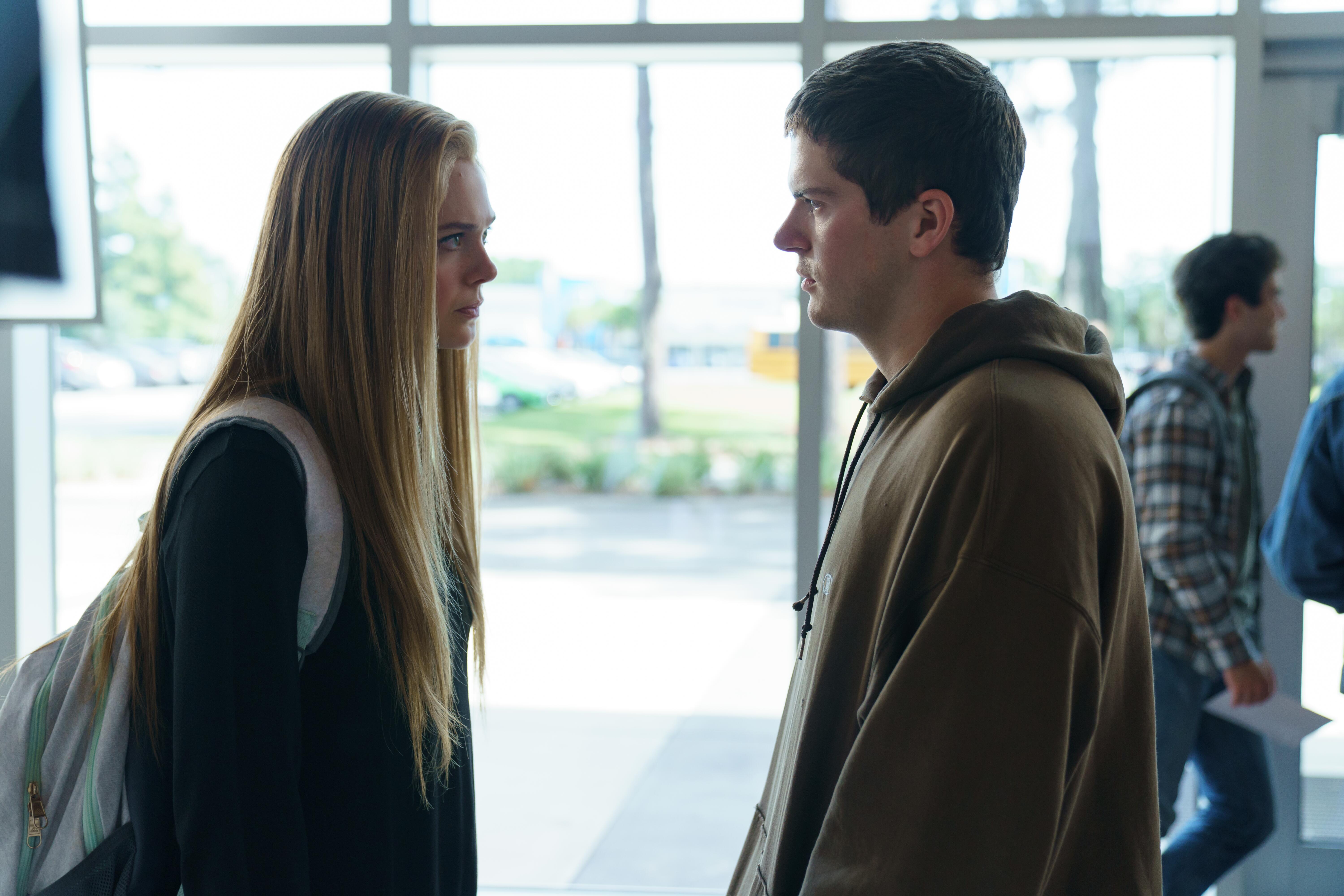 Elle Fanning as Michelle Carter and Colton Ryan as Conrad Roy in ‘The Girl From Plainville’ facing each other in a school.