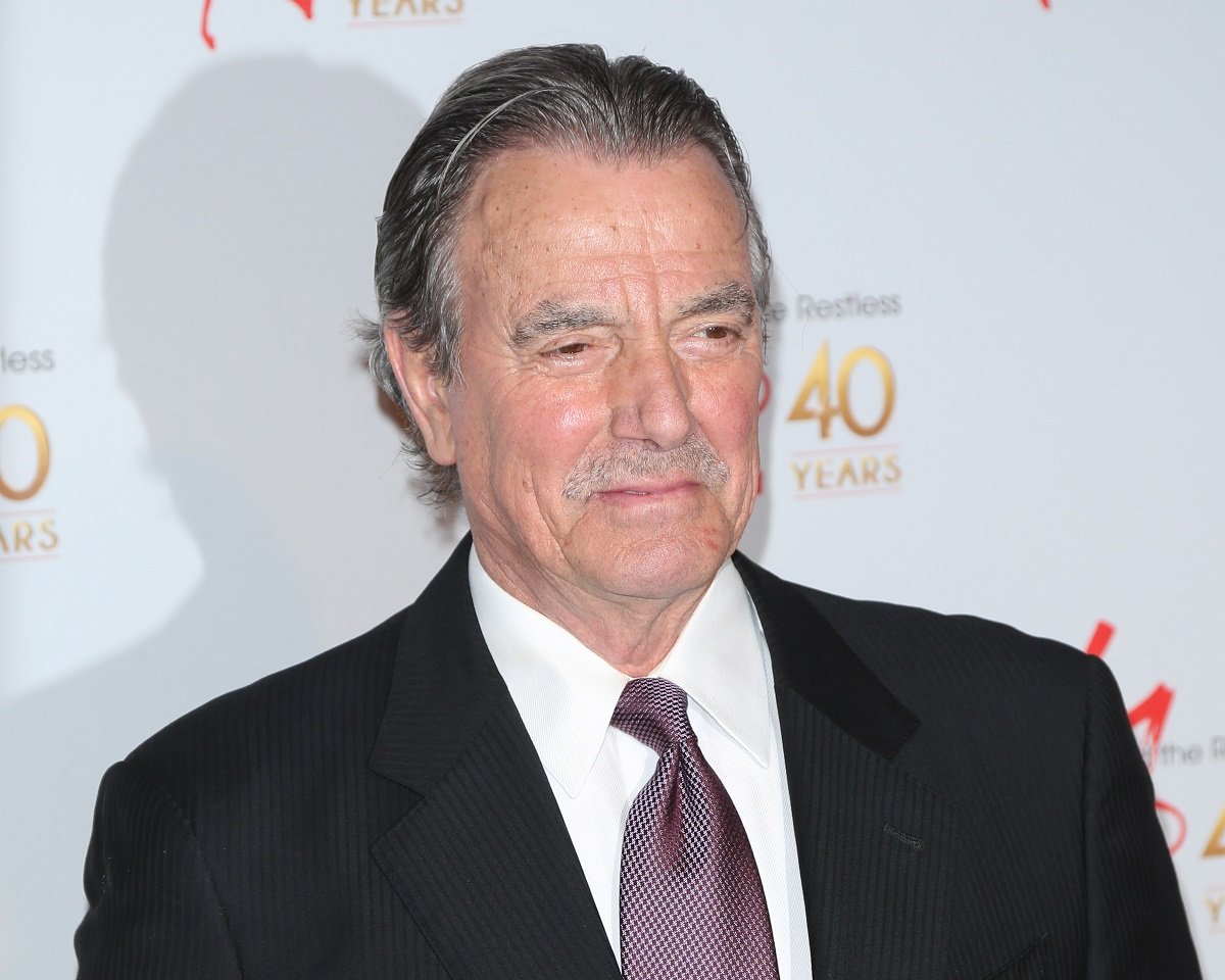 'The Young and the Restless' actor Eric Braeden wearing a black suit, white shirt, and purple tie.
