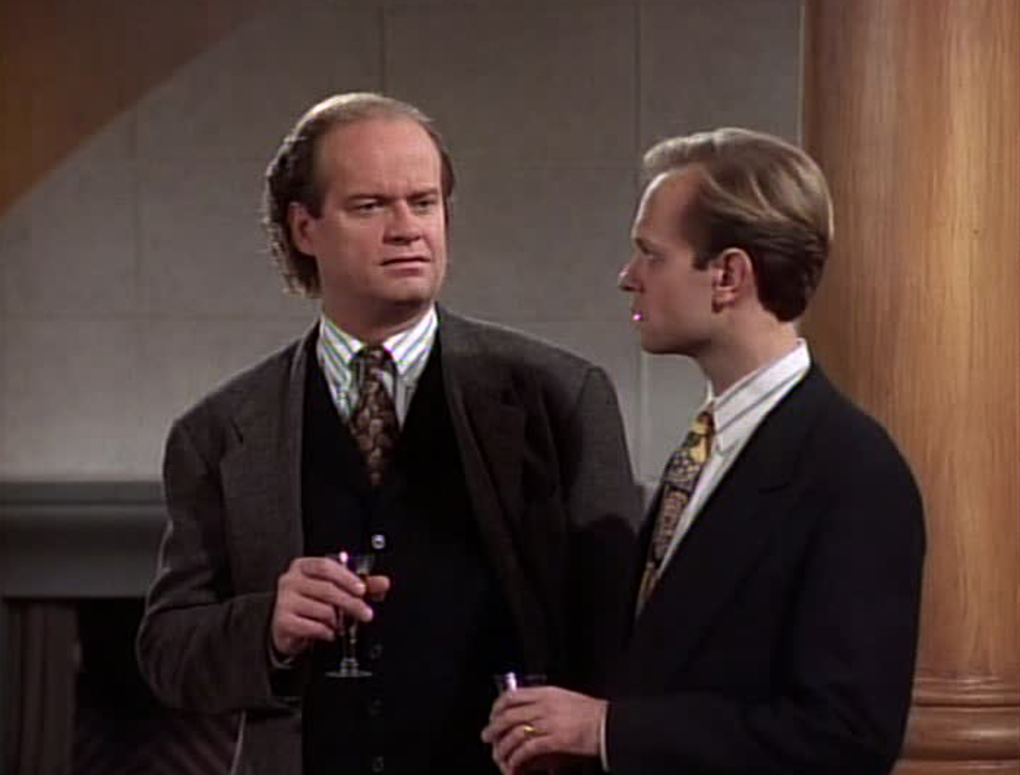 Dr. Frasier Crane and his brother, Dr. Niles Crane stand in Frasier's apartment