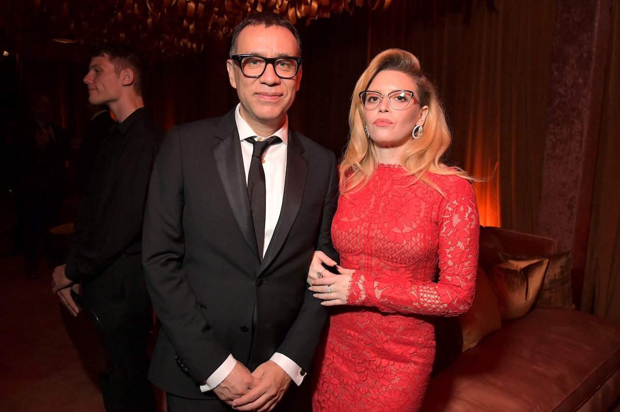 Fred Armisen in a suit and glasses and Natasha Lyonne in a red dress and glasses