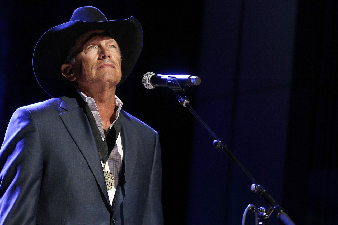 George Strait in a black cowboy hat, standing in front of a microphone