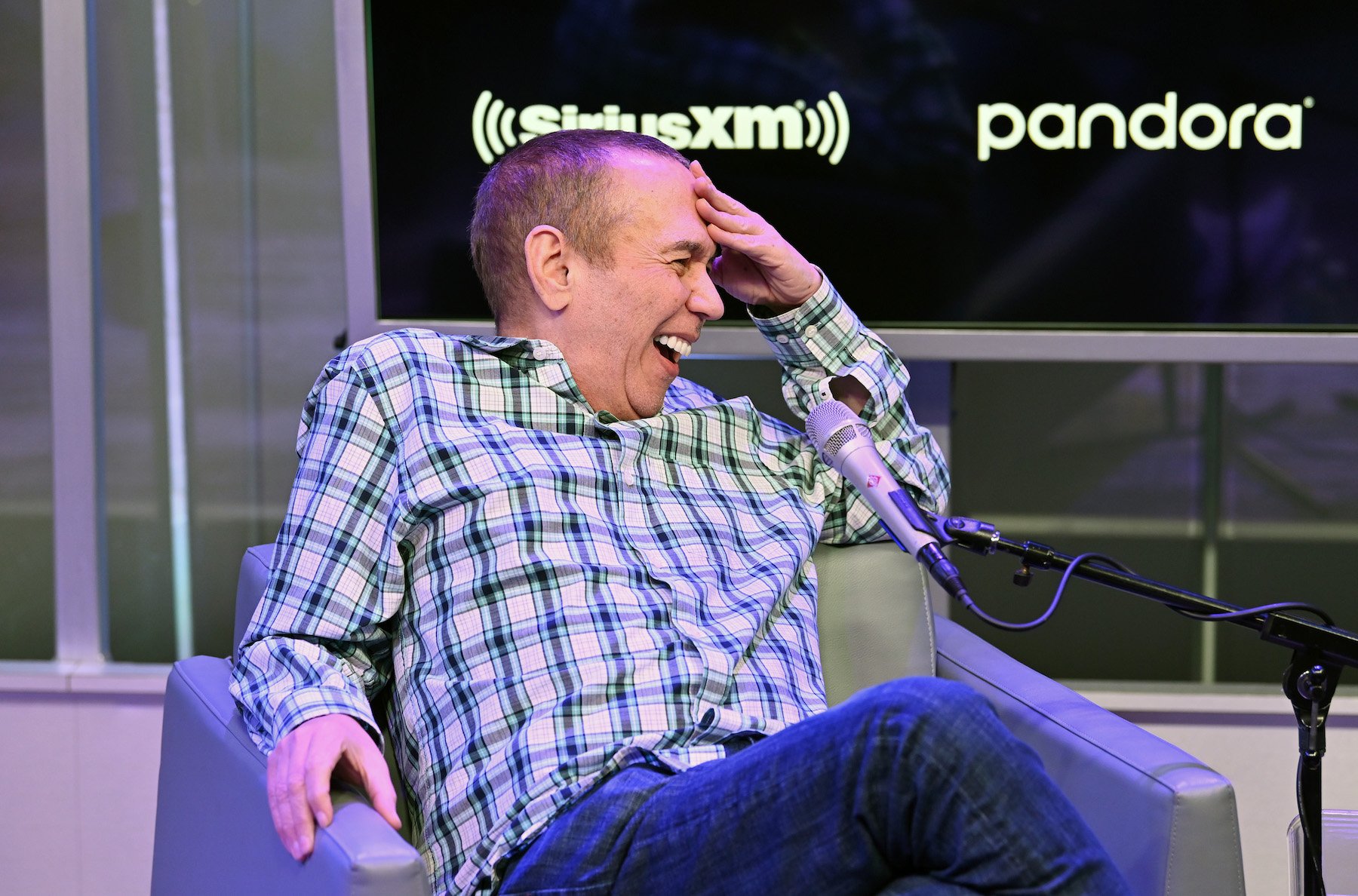 Gilbert Gottfried laughing while sitting and recording his podcast