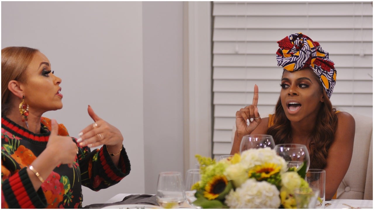 Gizelle Bryant and Candiace Dillard sitting at a table and talking to each other during an episode of 'The Real Housewives of Potomac'