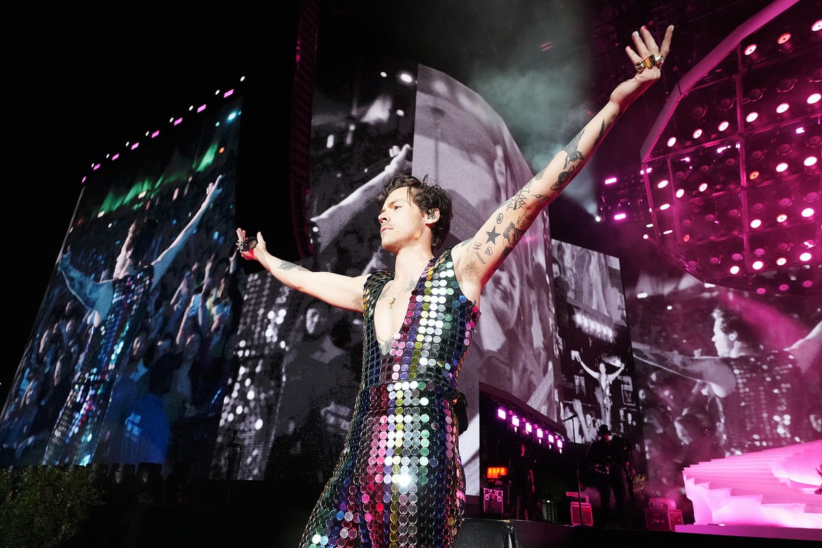 Wearing a rainbow jumpsuit, Harry Styles performs onstage at Coachella 2022 in Indio, California.