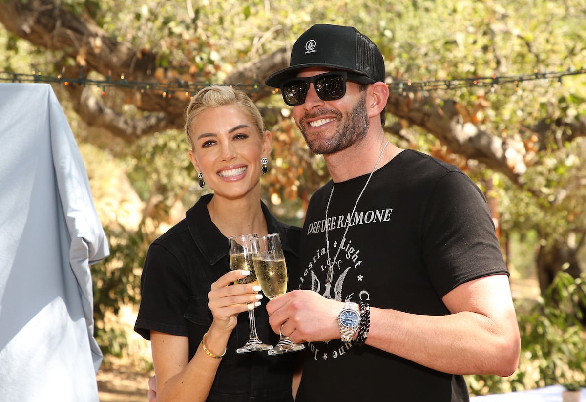Heather Rae Young and Tarek El Moussa clink champagne glasses at an event.
