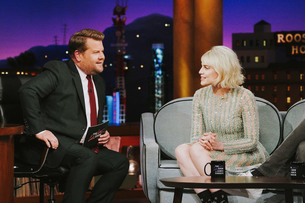 James Corden sits next to Lucy Boynton on the stage of 'The Late Late Show with James Corden'.