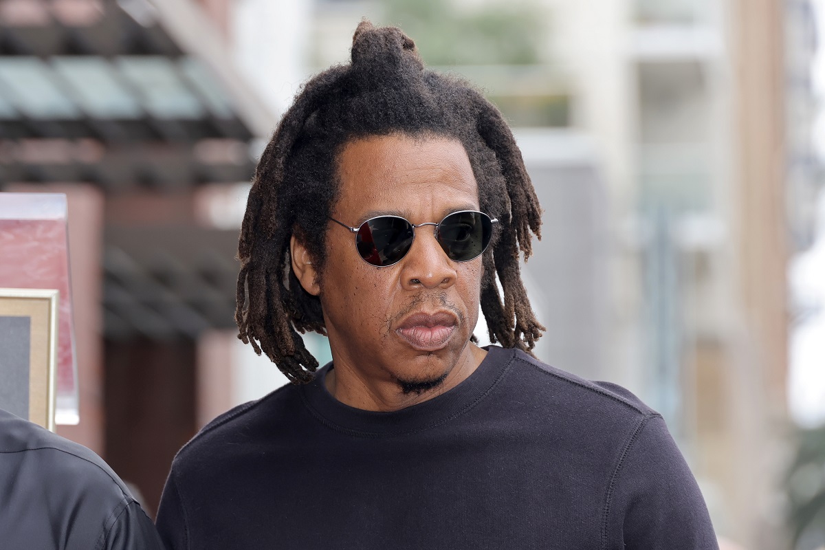 Jay-Z posing while wearing sunglasses and a black t-shirt.