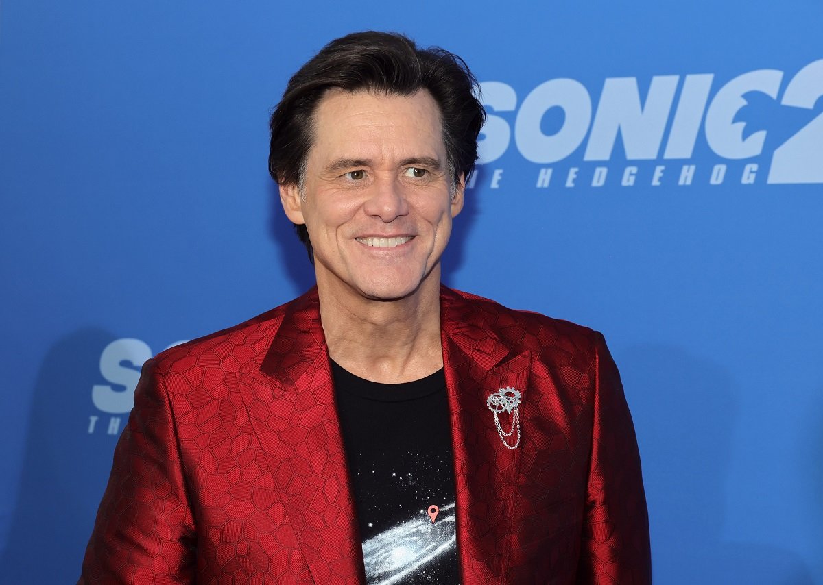 Jim Carrey smiling while wearing a red jacket.