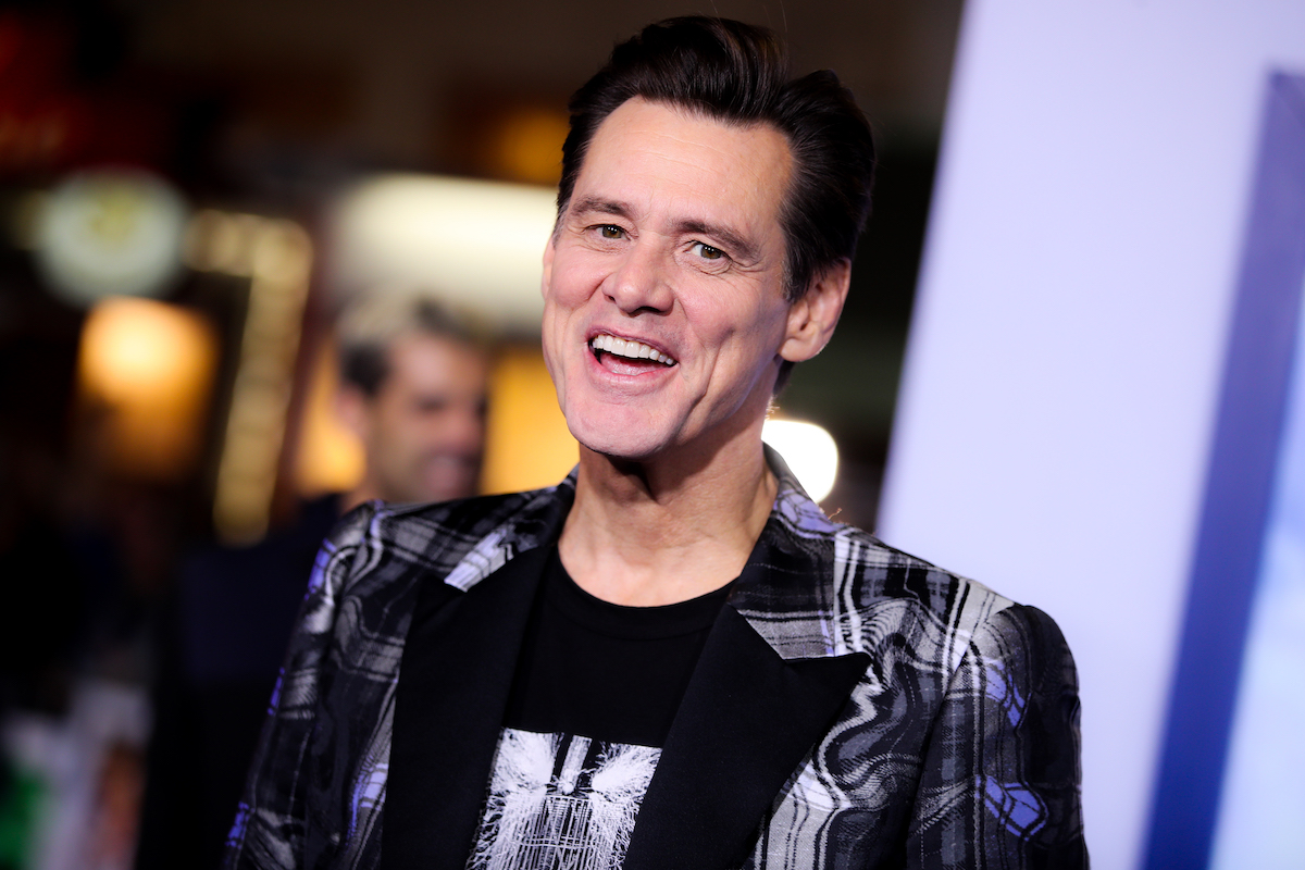 Jim Carrey is smiling and wearing a plaid shirt