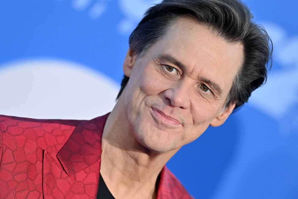 Jim Carrey wears a red outfit and poses on the red carpet