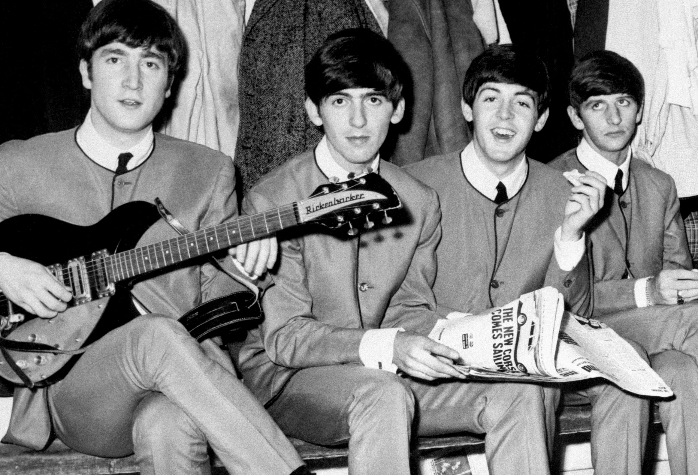 The Beatles' John Lennon, George Harrison, Paul McCartney, and Ringo Starr sitting on a bench