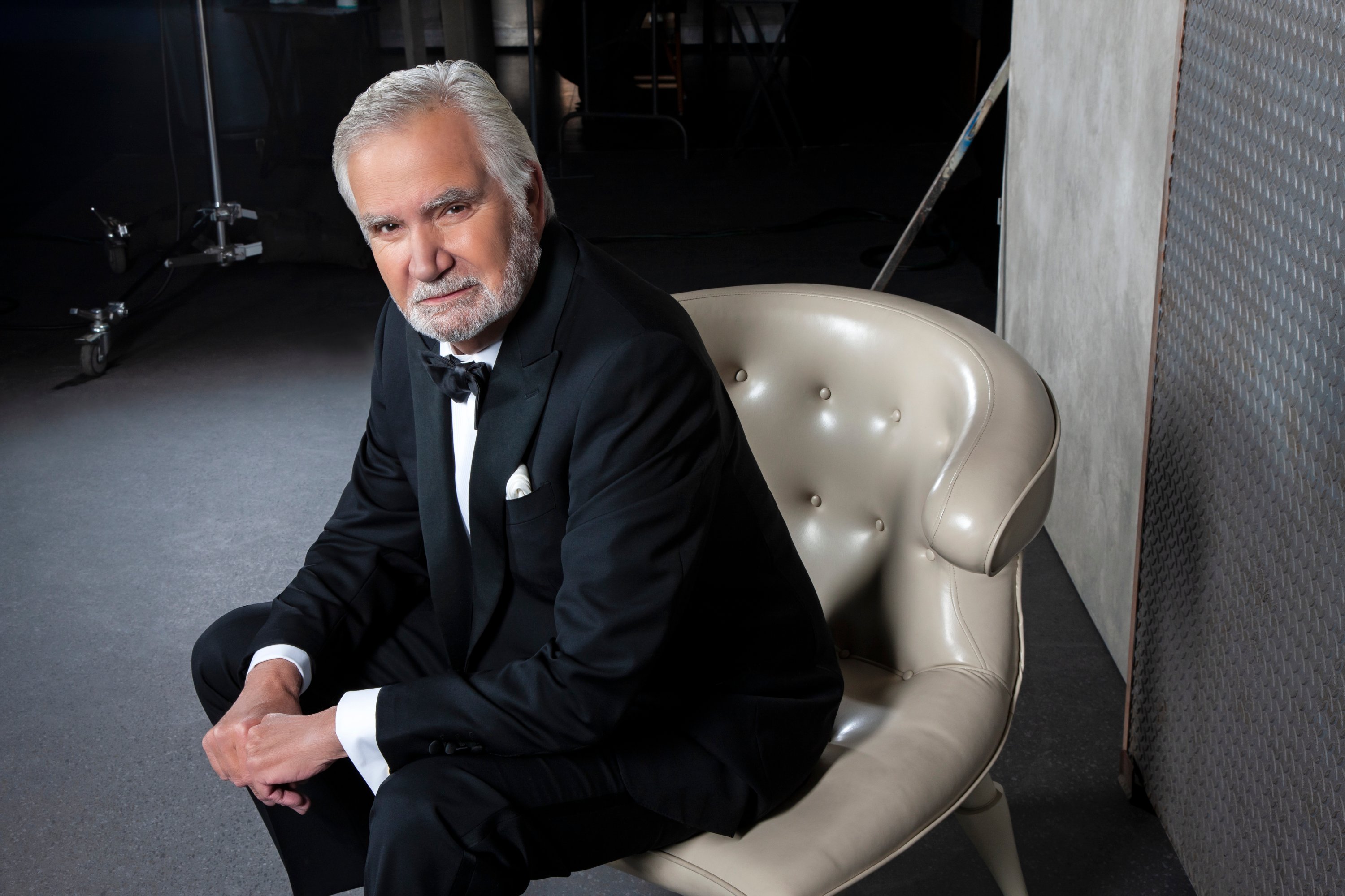 'The Bold and the Beautiful' actor John McCook wearing a tuxedo and sitting in a grey leather chair.