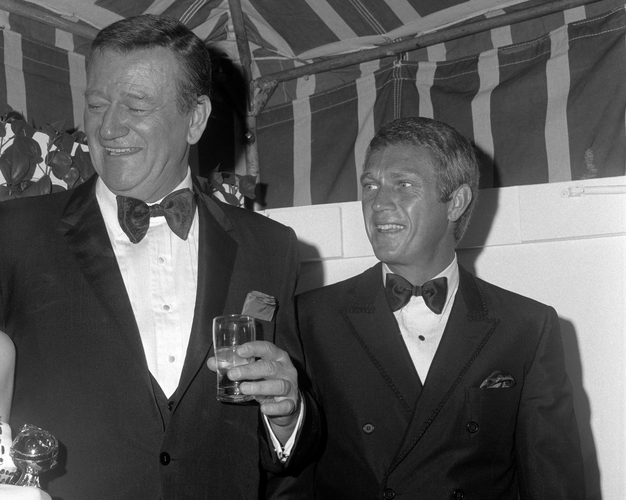 John Wayne and Steve McQueen at Golden Globes wearing tuxedos and smiling