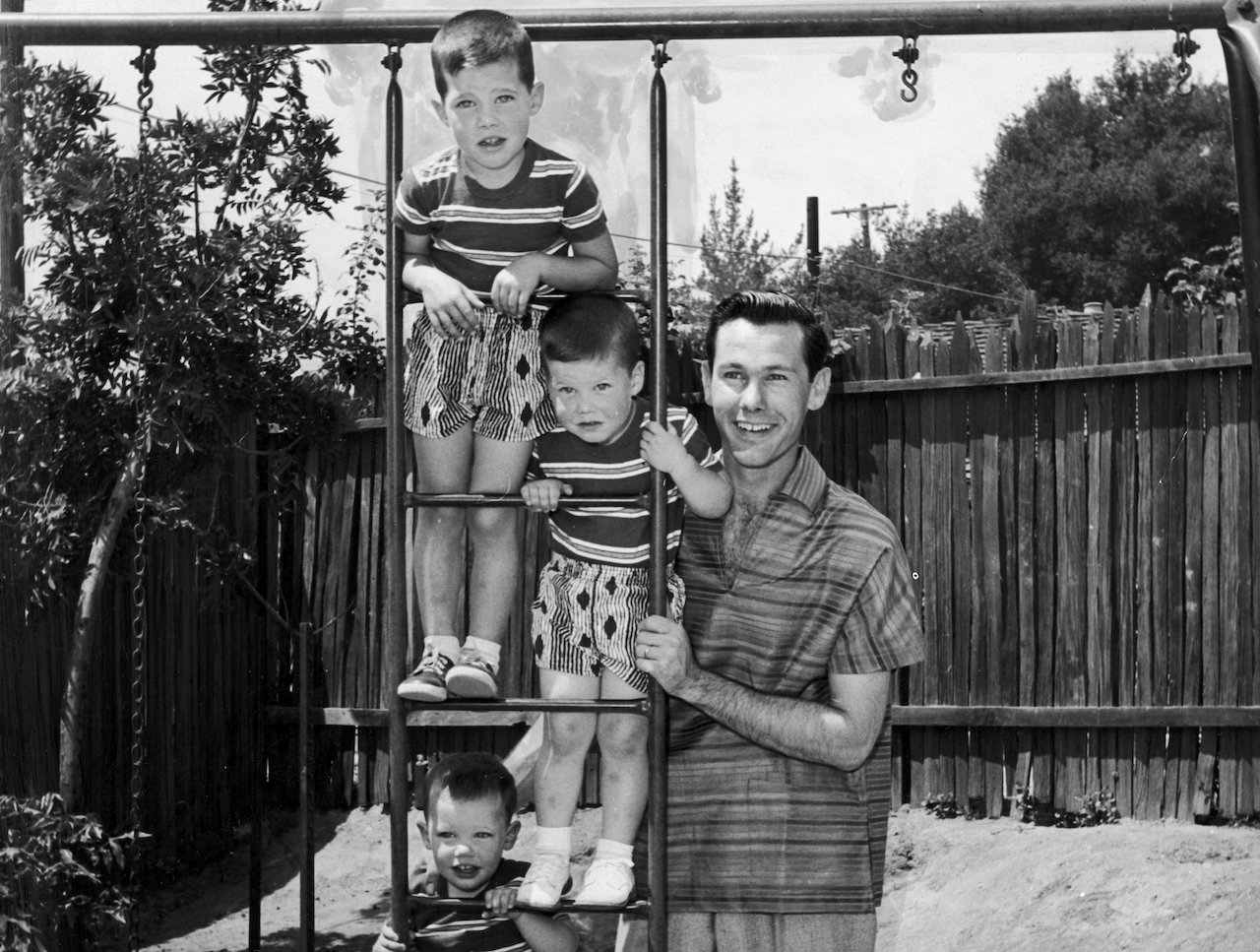 Johnny Carson poses with (top to bottom) Christopher, Richard and Cory Carson on a ladder in their back yard at home c. 1955