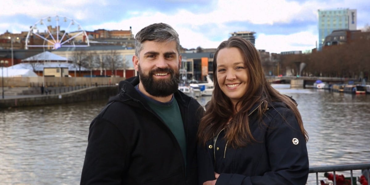 Rachel and Jon Walters standing in front of town in England on '90 Day Fiancé'.