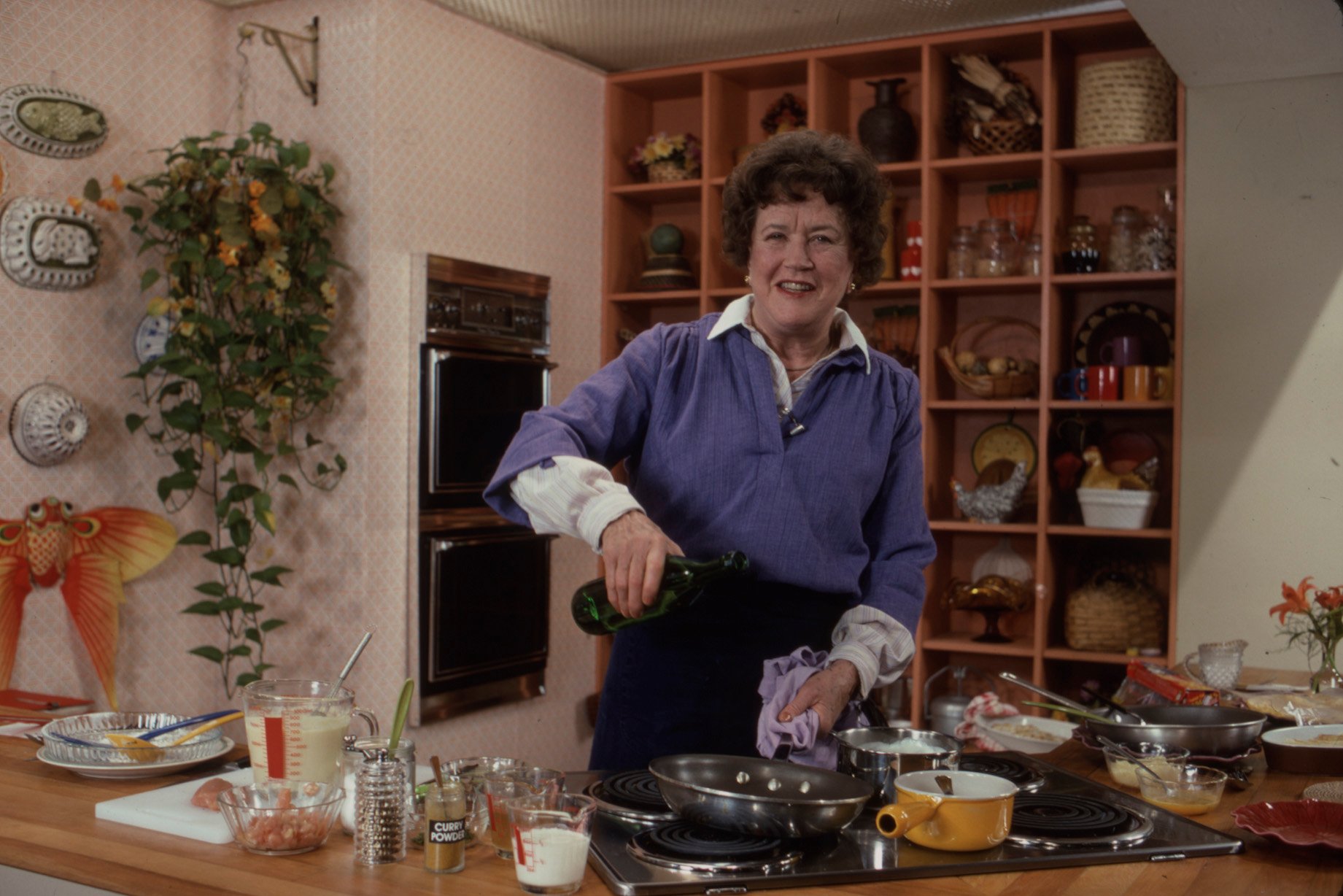 Julia Child stands in a kitchen and cooks in an undated photo