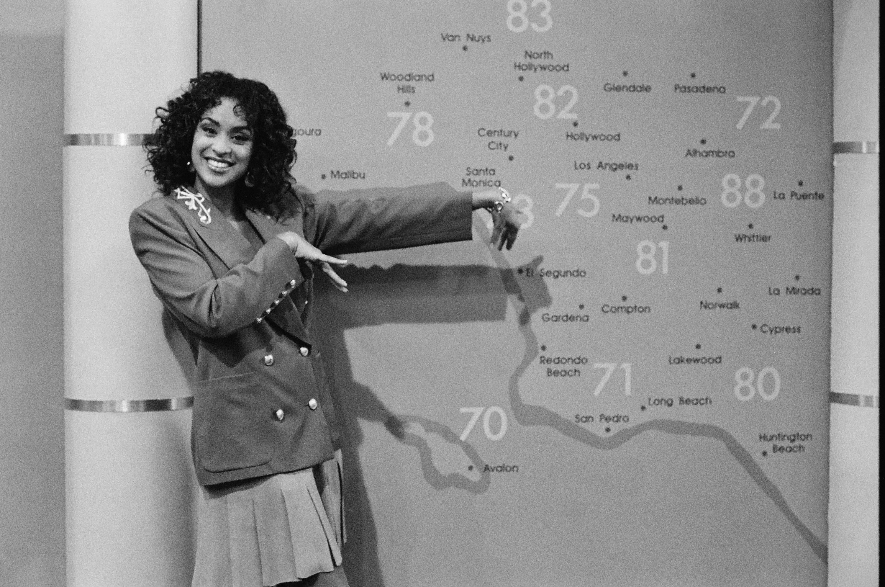 Karyn Parsons as Hilary Banks pointing to a large map during an episode of 'Fresh Prince of Bel-Air'