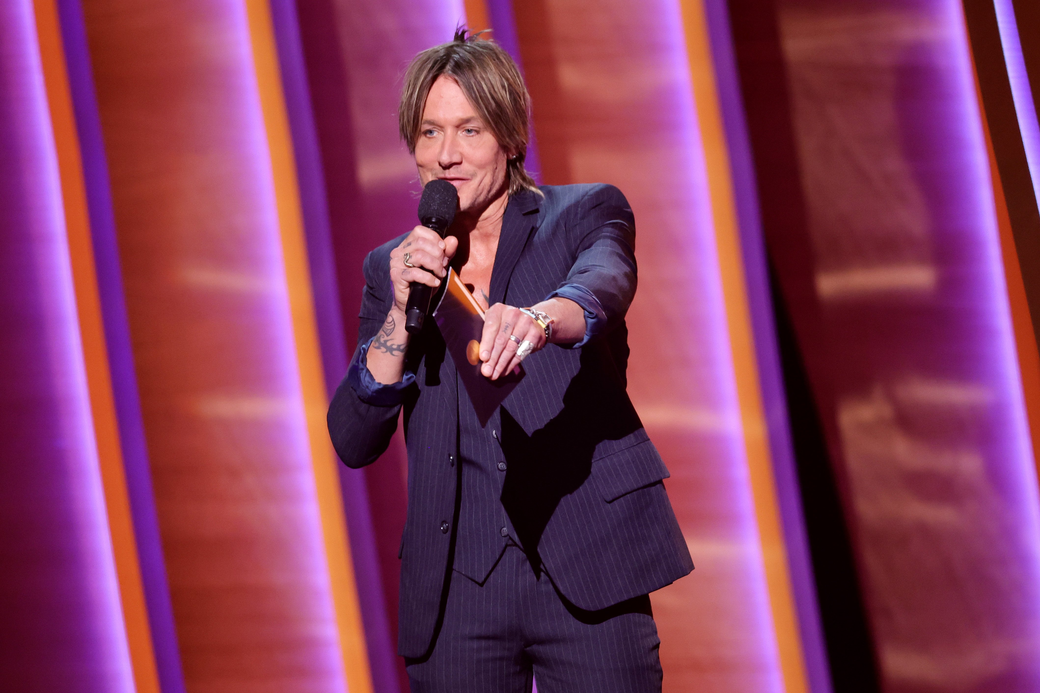Keith Urban, the musician behind 'Golden Road,' speaks into a mic on stage.