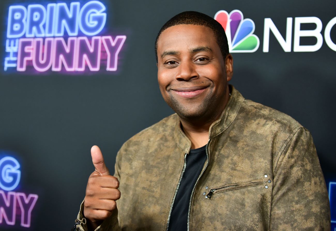 Kenan Thompson wears a brown jacket and gives a thumbs up.