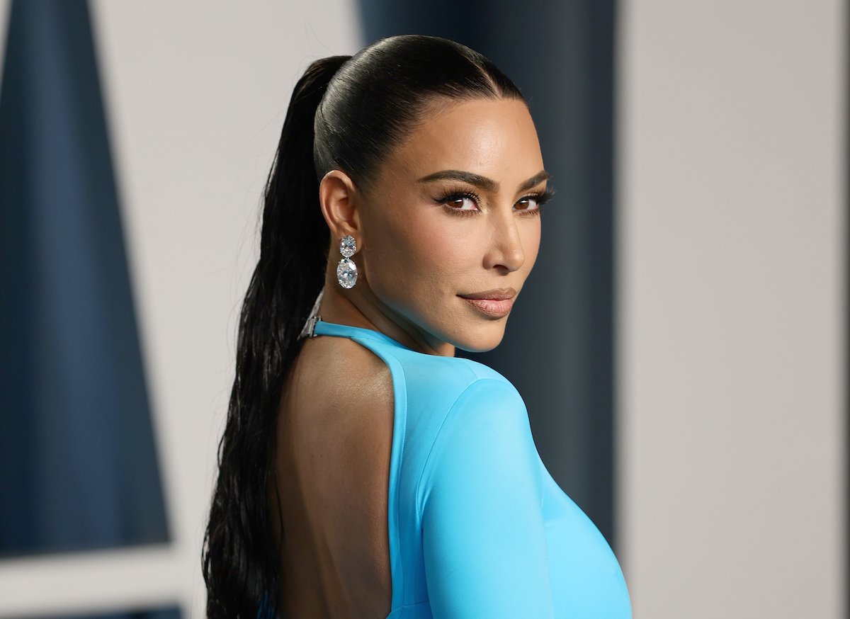 Kim Kardashian smiles and wears a bright blue dress at an event.