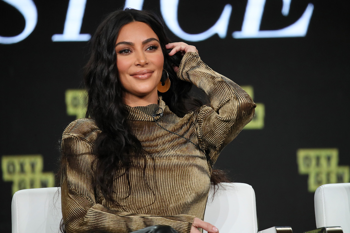 Kim Kardashian smiles and flips her hair over one shoulder.