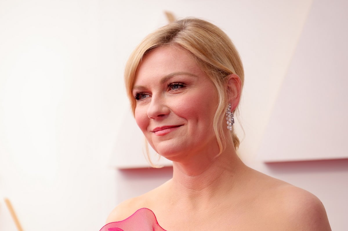 Kirsten Dunst smiling while wearing a pink dress.