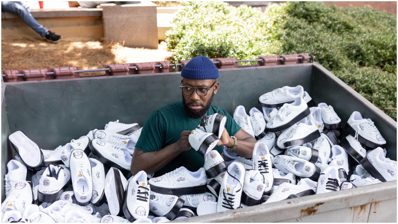 Lamorne Morris as Keef Knight in Hulu's 'Woke' holding shoes while in a dumpster filled with shoes